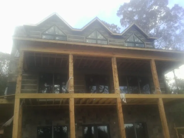 Dormers and porch framing on a large log home under construction — Roof Coating work by our crew in Plantation