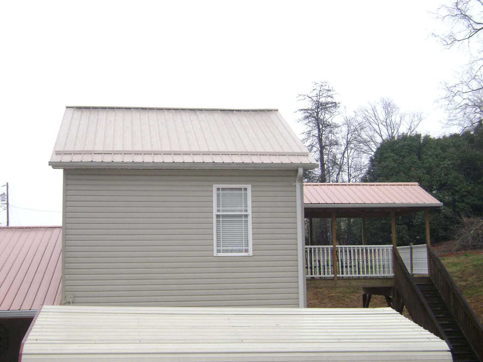 Tan metal roofs on a two story addition and attached porch, from a Roof Replacement job in Plantation