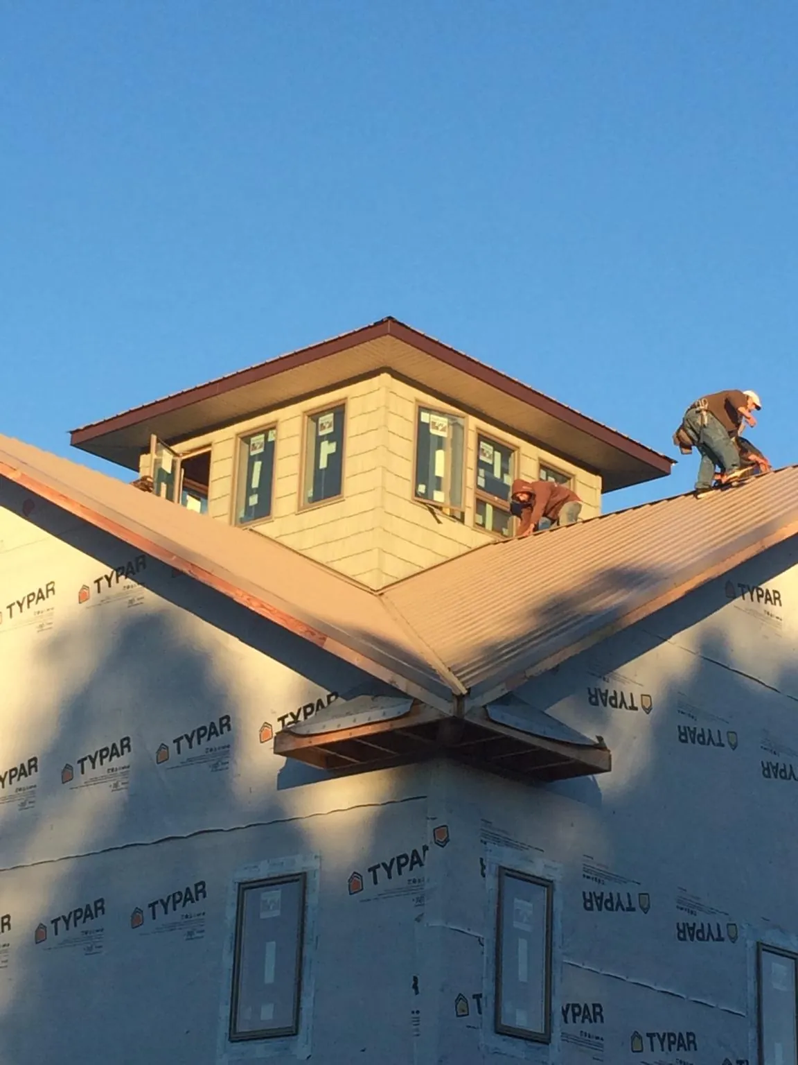 Roofers working around a rooftop cupola on a new metal roof at sunset — Roof Waterproofing in Plantation by Roofing Brothers
